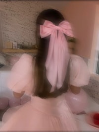 a girl in a pink dress with a pink bow